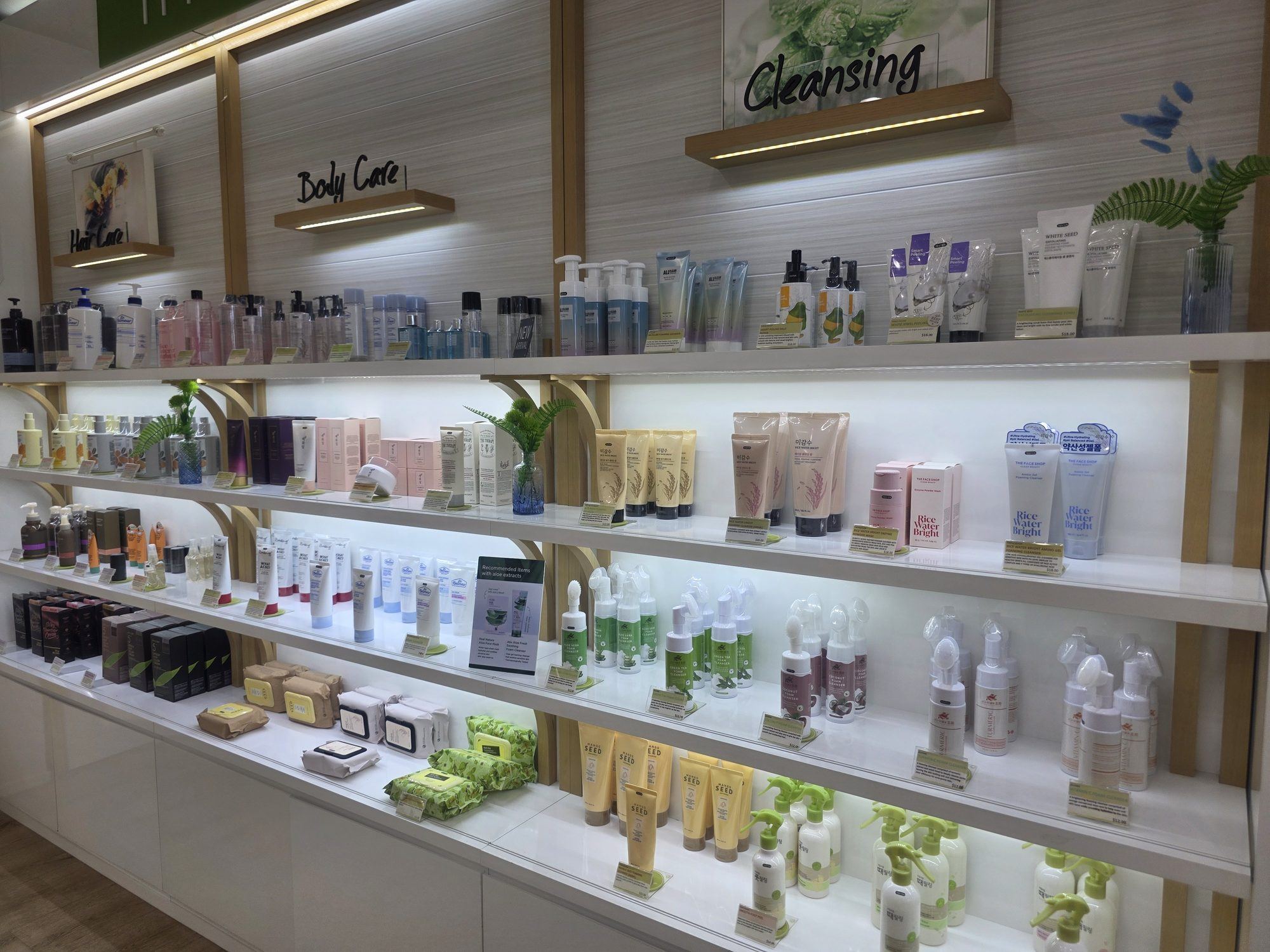 Backlit shop shelves of Korean cleansers, serums and skincare bottles