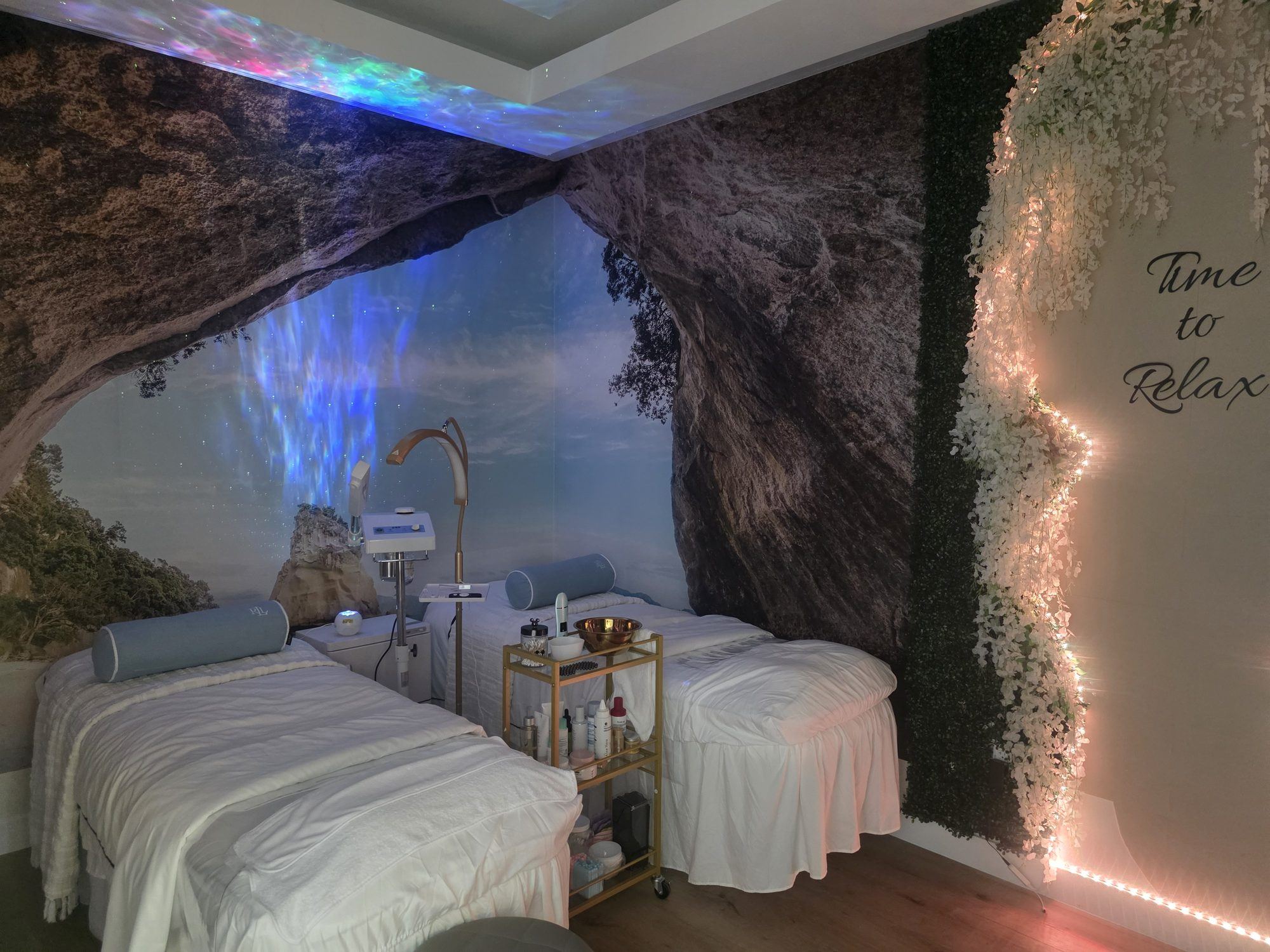 Dark treatment room with cave-textured stone walls, soft LED light, a draped facial bed and 'Time to Relax' lettering