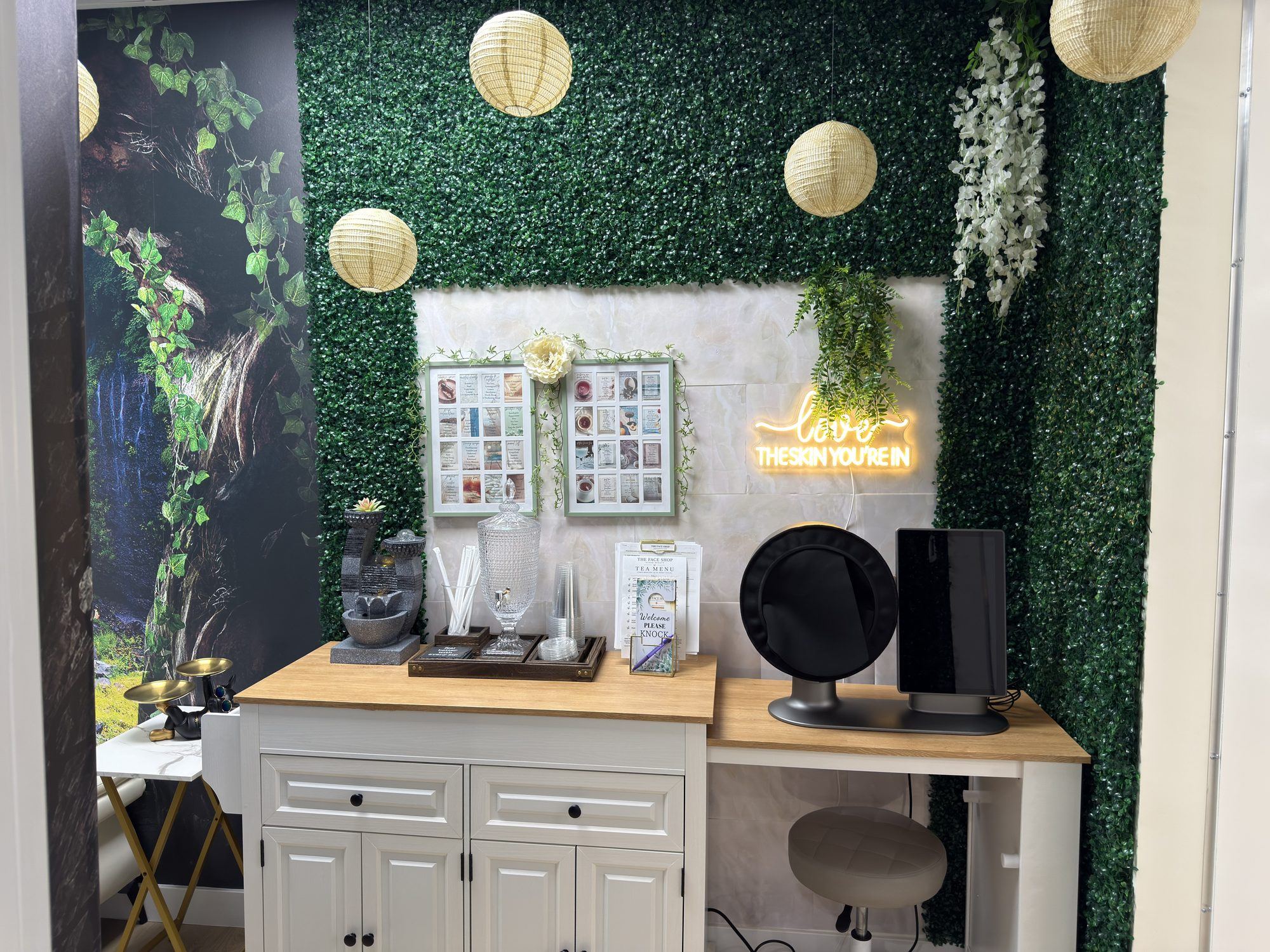 Green foliage wall with paper lanterns and a neon sign